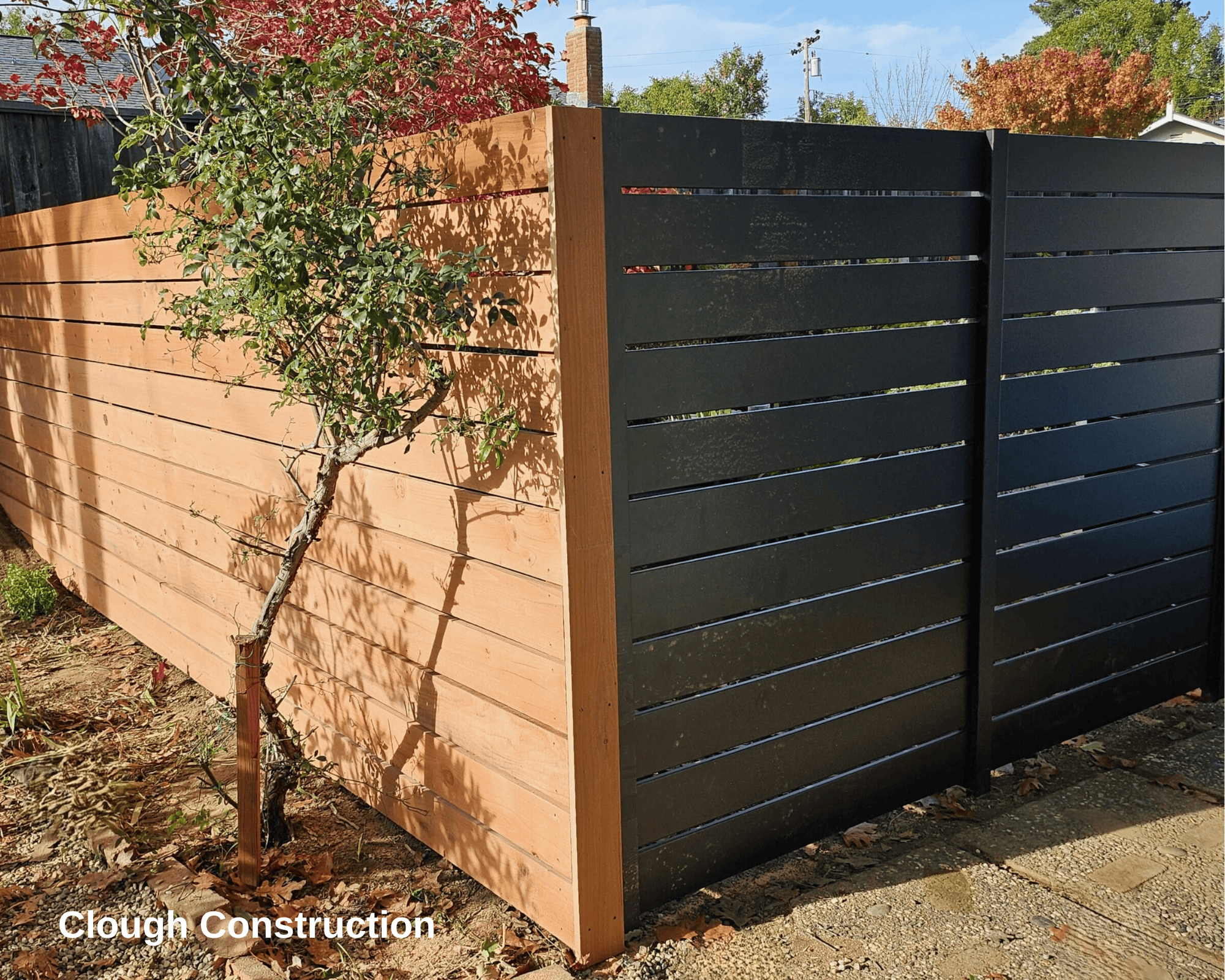 A black steel fence meeting at a corner with a light wooden fence.