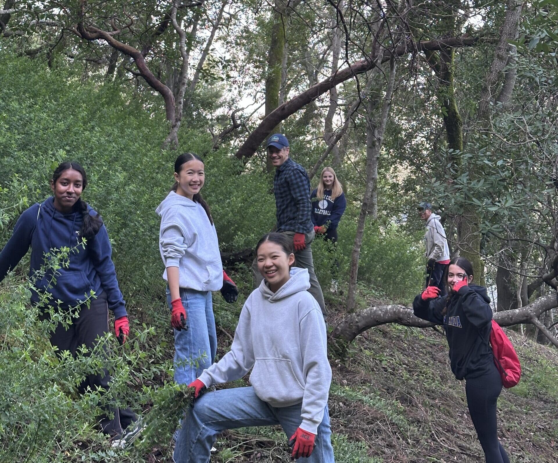 A group of middle school MSEL students in the forest, all of them facing and smiling at the camera.