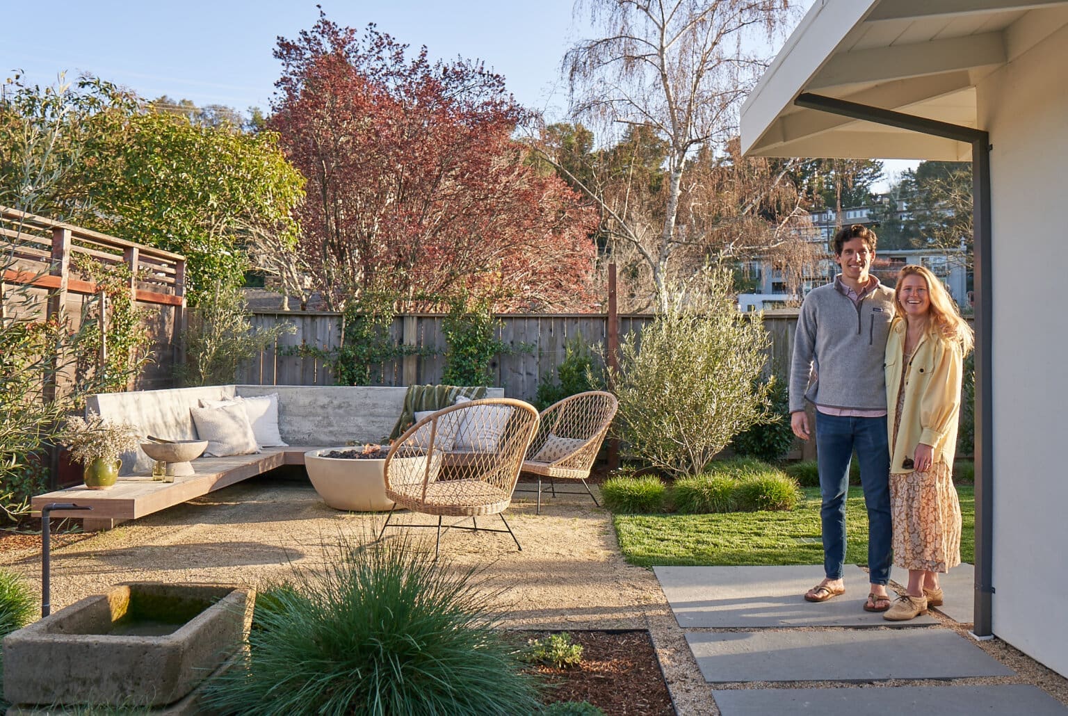 A young couple standing besides an outdoor seating area, smiling at the camera.