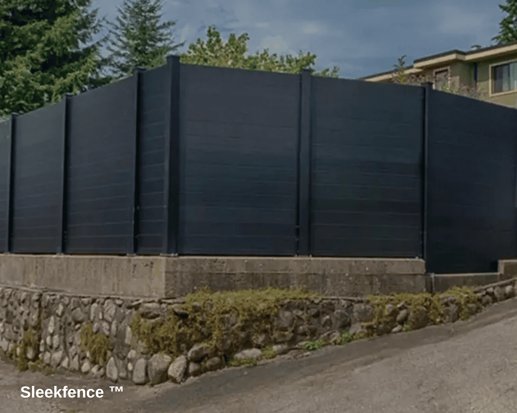 A large, black aluminum fence on top of a stone curbside.