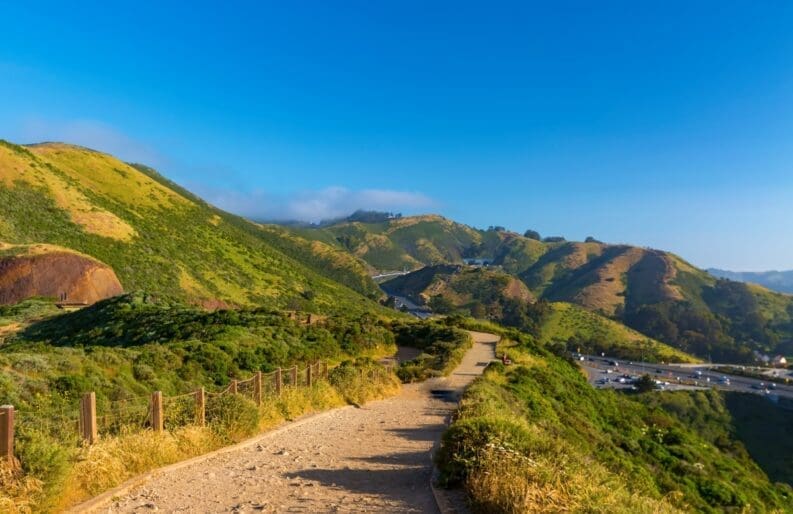 View from higher up of large, green hills and a bright blue sky.