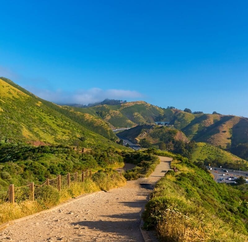View from higher up of large, green hills and a bright blue sky.