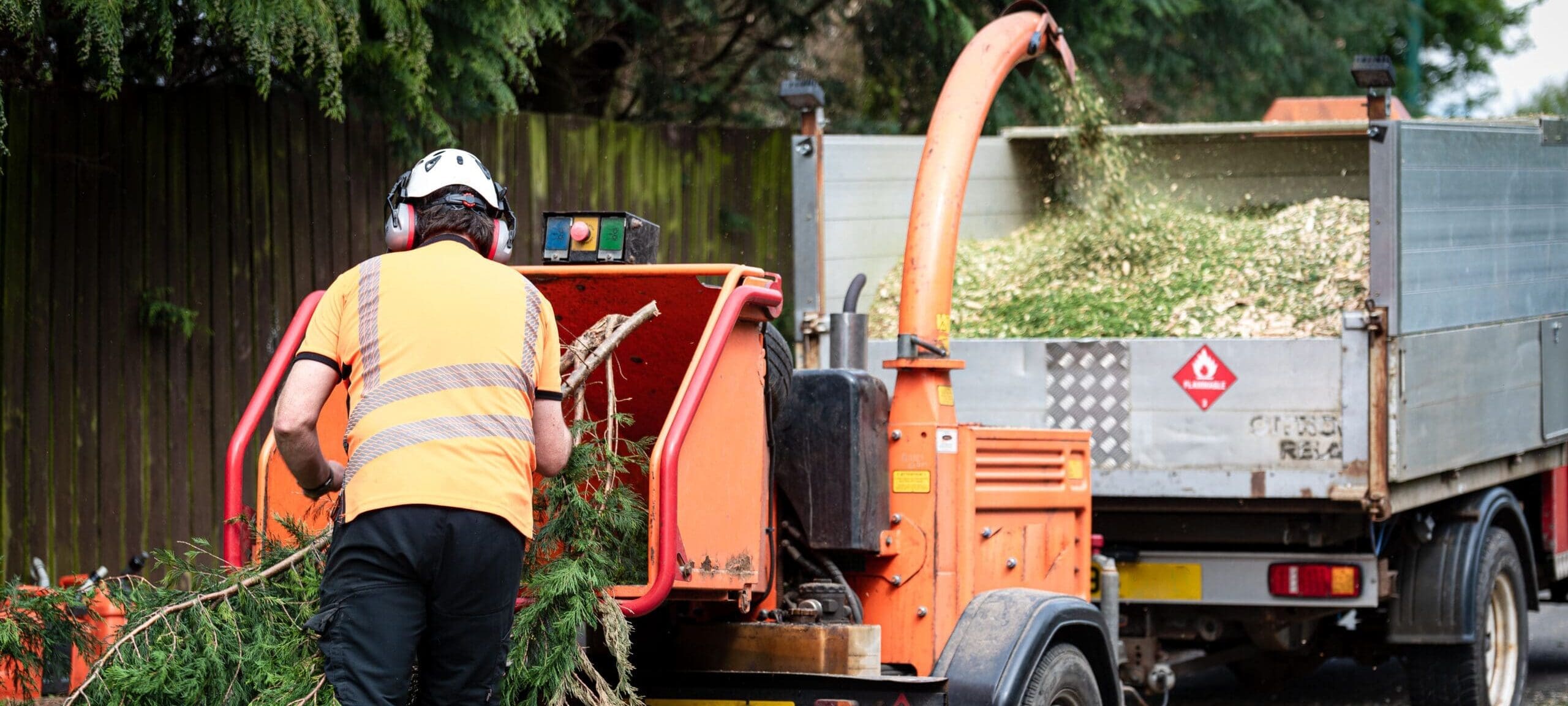Male,Arborist,Using,A,Working,Wood,Chipper,Machine.the,Tree,Surgeon