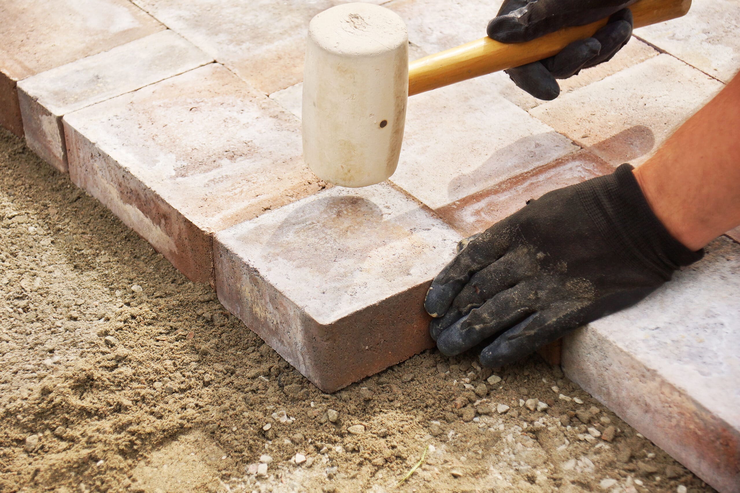 Installing,Paver,Bricks,On,Patio,,Mallet,To,Level,The,Stones