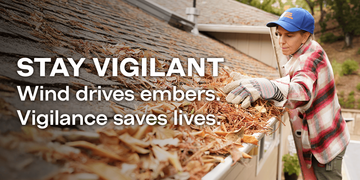 Woman clean leaves from roff gutters. "Stay Vigilant. Wind Drives embers. Vigilance saves lives"